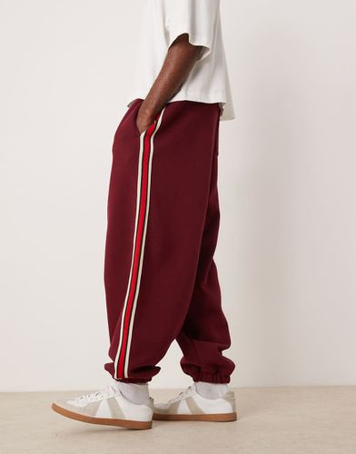 Pantalon de jogging bouffant oversize avec bandes latérales - Bordeaux - Asos Design - Modalova